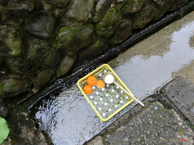 箱に入れられた『ニテコサイダー』とオレンジが清水に浸かって冷やされている様子