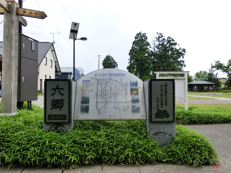 カマクラ畑の前にある六郷中央地区の案内図。両脇の石の下の方にには植田まさし先生のユウちゃんとハリザッコが刻まれている。